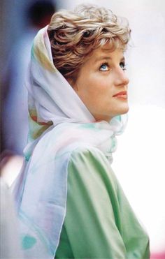 a woman wearing a green dress with a white scarf around her head and looking off to the side