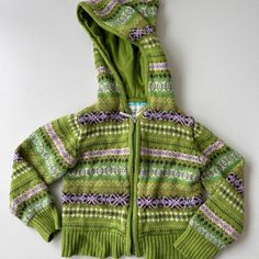 a child's green and purple sweater with hoodie on the front, sitting on a white surface