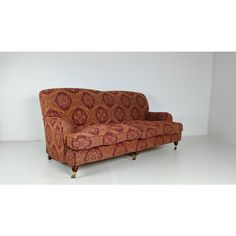 an orange and red couch sitting on top of a white floor next to a wall