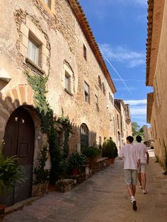 two people walking down an alley between buildings