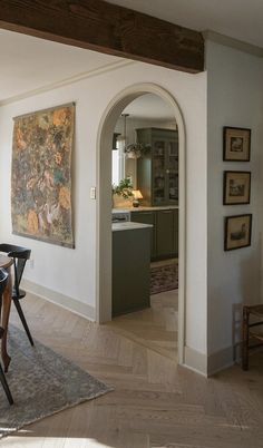 a dining room table and chairs in front of an archway leading to the kitchen area