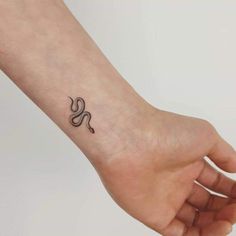 a small black and white snake tattoo on the wrist