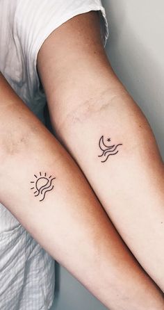 two people with matching tattoos on their arms, one is holding the other's arm