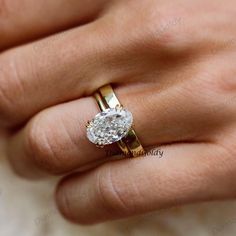 a woman's hand with a diamond ring on top of her finger and gold band