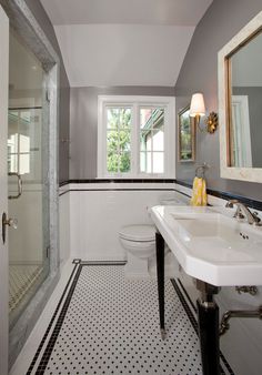 a bathroom with black and white tile flooring and walls, along with a walk in shower