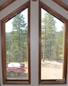 two large windows in the corner of a room with a red truck parked on the other side