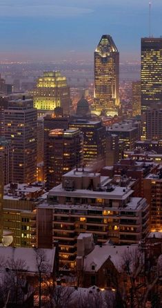 the city is lit up at night with snow on the ground and buildings in the foreground