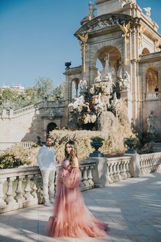 a man and woman standing next to each other in front of a fountain