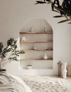 a bedroom with white walls and shelves filled with vases