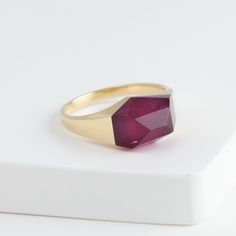 Description Bororo's signature rock ring in a smaller size with a beautiful one-of-a-kind red tourmaline stone from Brazil. Mini rock rings are perfect for those who love the innovative design of rock rings and want to wear it every day. The irregular geometrical cut of the stone makes this ring edgy and contemporary. This tourmaline is of a deeper red color which is rare in tourmaline, so it's a collector's piece which is difficult to reproduce once sold. The pieces in the rock series are made by applying the Japanese traditional method 'Dozuri'. This technique shapes the ring when the stone and metal are attached to create its seamless look. Every single rock ring is unique because from the designer's selection of the rough stone to the traditional craftsman cutting and smithing the ring Modern Ruby Ring For Promise, Modern Ruby Jewelry As A Gift, Modern Ruby Gemstone Ring, Modern Ruby Gemstone Jewelry, Fine Ruby Signet Ring, Fine Ruby Signet Ring With Gemstone, Modern Ruby Ring For Gift, Modern Ruby Ring As Gift, Modern Garnet Ring Jewelry