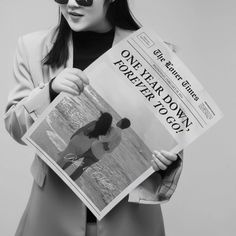 a woman in sunglasses holding up a newspaper