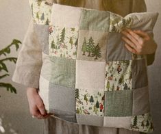 a woman holding a patchwork pillow with trees on it