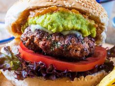 a burger with lettuce, tomato and guacamole