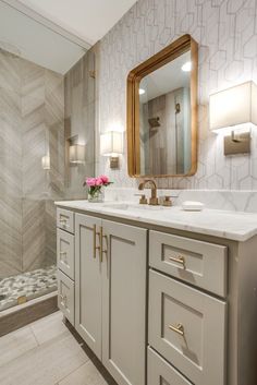 a bathroom with marble counter tops and gold accents on the mirror, along with a walk in shower