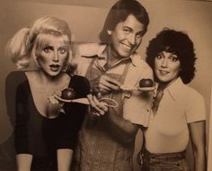 three people are posing for a photo while holding scissors and an apple in front of them