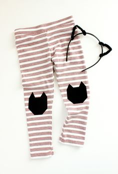 a pair of leggings with black cat patches on the bottom and white stripes