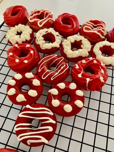 red and white frosted donuts sitting on a cooling rack next to each other