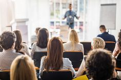 a group of people sitting in front of a man giving a presentation to an audience