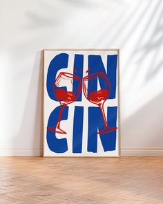 a blue and red poster with two glasses of wine on it, against a white wall