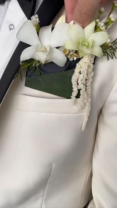 a close up of a person wearing a suit and tie with flowers on the lapel