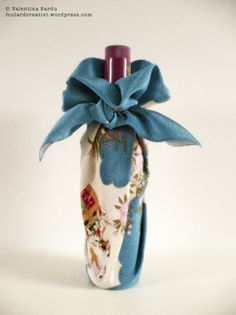 a bottle wrapped in fabric with a bow on the top and ribbon tied around it