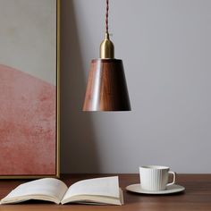 an open book sitting on top of a wooden table next to a cup and saucer