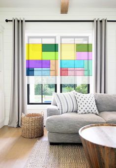 a living room filled with furniture and large windows covered in rainbow colored squares on the wall