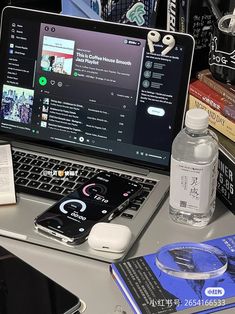 an open laptop computer sitting on top of a desk next to a pile of books