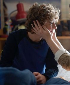 a woman talking to a child who is sitting on a bed with her head in her hands