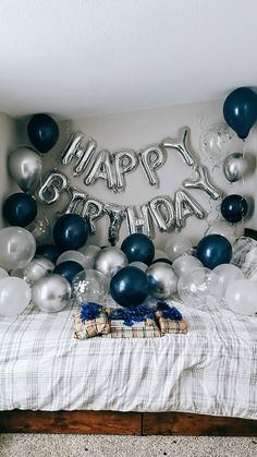 a bed topped with balloons and a happy birthday sign