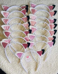 pink and black cat ears with glitter on them are sitting on a white carpet next to a pair of scissors