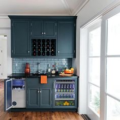 a kitchen with dark green cabinets and wood flooring, along with an ice chest