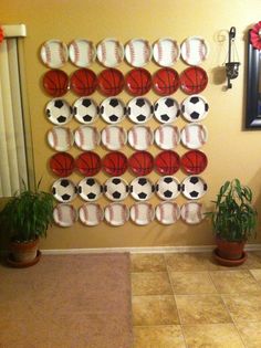 a basketball themed wall hanging on the side of a room with potted plants in front of it