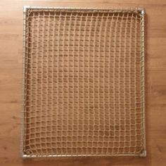 a piece of metal mesh sitting on top of a wooden floor