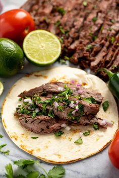 the steak is on top of a tortilla with cilantro and lime