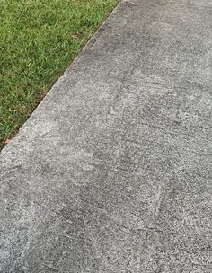 an empty sidewalk in the middle of a grassy area