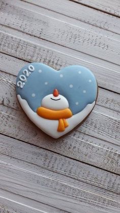 a cookie shaped like a snowman on top of a wooden table next to a heart