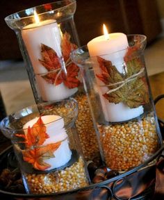 some candles are sitting in glass vases with leaves on them