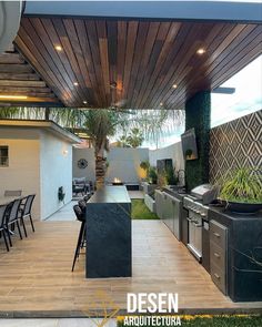 an outdoor kitchen and dining area with grills, table, chairs, and potted plants