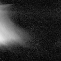 a black and white photo of the moon in the sky with some clouds around it