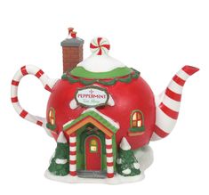 a red and green teapot shaped like a house with candy canes on the roof