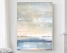 an abstract painting hangs on the wall above a couch in a living room with white walls