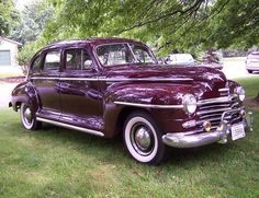 an old purple car is parked in the grass