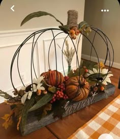 an arrangement of pumpkins and leaves on a table