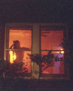 a woman is standing in the window at night