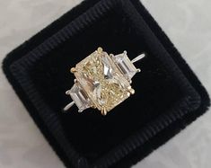 a fancy yellow diamond ring sitting on top of a black velvet box