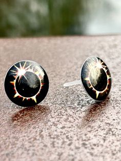 pair of black and white earrings sitting on top of a stone table next to each other