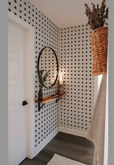 a bathroom with black and white wallpaper has a round mirror on the wall next to it