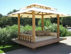 a wooden bench with cushions under a white umbrella