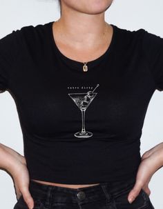 "Introducing the epitome of trendy chic - our \"Extra Dirty\" Martini Crop Top. Elevate your style game with this must-have piece that effortlessly blends downtown girl aesthetic, baby tee Y2K vibes, and clean girl aesthetic. Embrace your inner trendsetter with the downtown girl aesthetic, featuring a sleek martini graphic that adds an edgy, urban vibe to your wardrobe. The \"Extra Dirty\" statement takes it up a notch, giving you that extra dose of attitude for a standout look. Designed in a baby tee Y2K style, this crop top perfectly fuses nostalgia with contemporary flair. The snug fit and cropped silhouette create a sassy yet comfortable piece, making it a go-to choice for pairing with high-waisted jeans or a cute skirt. It's the ultimate statement piece for those who love to stay on t Cute Fitted T-shirt For Party, Cute Black Party Tops, Fitted Graphic Print Party Tops, Fitted Graphic Print Tops For Party, Fitted Graphic Print T-shirt For Party, Cute Short Sleeve Party Tops, Y2k Graphic Print Party Tops, Cute Party Top With Crew Neck, Cute Fitted Party T-shirt